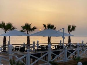 een groep tafels met parasols op het strand bij Kamarina Resort in Ragusa