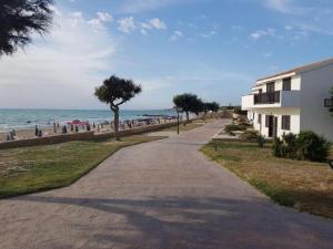um passeio ao lado de uma praia com um edifício e o oceano em Kamarina Resort em Ragusa