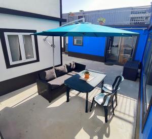 a patio with a table and a blue umbrella at Vila Arrifes Guesthouse Downstairs in Ponta Delgada