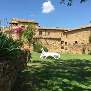 una silla blanca sentada en un patio junto a un edificio en Villa Fonte all'Oppio con area piscina recintata, en Pienza