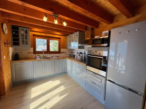 a kitchen with white cabinets and a refrigerator at Charming, cosy chalet nestled in a breathtaking surrounding with spectacular, stunning mountain views in La Chapelle-dʼAbondance