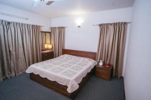 a bedroom with a bed and two tables and curtains at Anand Homestay in Srinagar