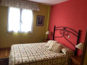a bedroom with a bed with a red wall at Casa cerca de la playa en Somo in Somo
