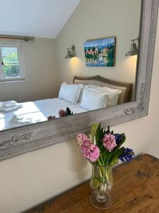 een slaapkamer met een spiegel en een vaas met bloemen bij A family and dog friendly haven, The Hayloft. in Saxmundham