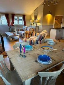 a wooden table with plates and a candle on it at A family and dog friendly haven, The Hayloft. in Saxmundham