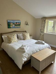 Un dormitorio con una gran cama blanca y una ventana en A family and dog friendly haven, The Hayloft., en Saxmundham