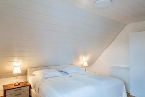 1 dormitorio con 1 cama blanca y 2 lámparas en Ferienwohnung am Schlossberg en Odelzhausen