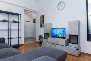 a living room with a couch and a tv on a wall at Modern Cozy 1 Bd Piraeus Perfection Apt in Piraeus