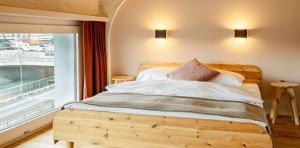 a bedroom with a wooden bed with a large window at Silo Design & Boutique Hostel Basel in Basel