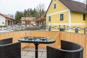 a patio with a table and chairs and a yellow house at Ferienwohnung am Schlossberg in Odelzhausen