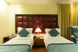 a hotel room with two beds and a desk at The Grand Orion - Kailash Colony in New Delhi