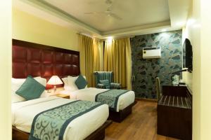 ein Hotelzimmer mit 2 Betten und einem Stuhl in der Unterkunft The Grand Orion - Kailash Colony in Neu-Delhi