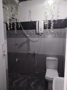 a bathroom with a toilet and flowers on the wall at Ella Way Resort in Peradeniya