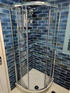 a shower in a bathroom with blue tiles at Homebird Property - Waltz House in Sheffield