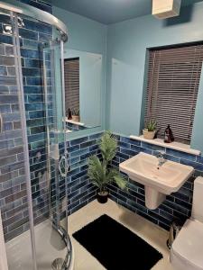 a blue bathroom with a sink and a shower at Homebird Property - Waltz House in Sheffield