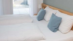 Una cama blanca con almohadas azules. en Ferienwohnung Kirsche - Obsthof Steffelin, en Heraclión