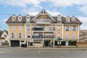 un grand bâtiment jaune avec un toit en gambrel dans l'établissement Urban Balcony - Avec parking à Villiers-sur-Marne, à Villiers-sur-Marne