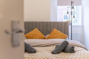 a bed with yellow pillows and gray socks on it at Open Mind Property - Luxury Apartment Near Hospital & Underground Free Parking for 2 Vehicles in Southampton