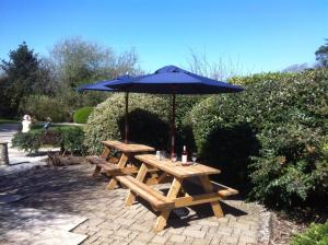 een houten picknicktafel met een blauwe paraplu bij Spring Barn at Bolberry Court in Hope-Cove