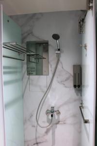 La salle de bains est pourvue d'une douche et de murs en marbre. dans l'établissement Twin Star Inn, à Taipei