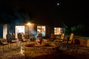 a group of chairs sitting around a fire pit at night at Sondela Nature Reserve & Spa Makhato Lodges in Bela-Bela
