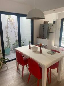 Acogedora casa en Santo Tome في سانتو تومي: مطبخ مع طاولة بيضاء وكراسي حمراء