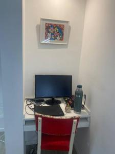 a desk with a computer monitor and a red chair at Acogedora casa en Santo Tome in Santo Tomé