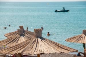 a group of umbrellas on a beach with people in the water at Sun Beach Lindos in Lartos