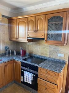eine Küche mit Holzschränken und einem Herd mit Backofen in der Unterkunft Faro Park Villa Bella heated Pool in Playa Blanca
