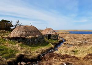 two huts in a field next to a river at Bayview 1-Bed Cottage in Isle of Lewis in Bragor