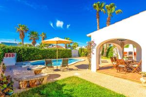 a patio with a table and chairs and an umbrella at Villa Miguel Dos in Cala'n Bosch