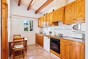 a kitchen with wooden cabinets and a table in it at Villa Miguel Dos in Cala'n Bosch