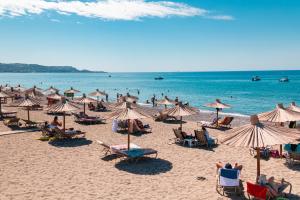 una spiaggia con molte sedie e ombrelloni e l'oceano di Sun Beach Lindos a Lárdos