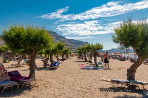 una spiaggia con palme e persone sulla sabbia di Sun Beach Lindos a Lárdos