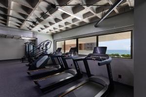 eine Gruppe von Laufbändern in einem Fitnessraum mit Fenster in der Unterkunft Beach Class #1104 - Quádruplo por Carpediem in Recife