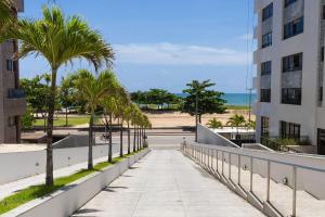 ein Bürgersteig neben einem Gebäude mit Palmen und dem Strand in der Unterkunft Beach Class #1104 - Quádruplo por Carpediem in Recife