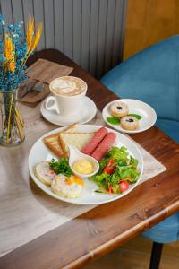 a table with a plate of breakfast foods and a cup of coffee at Dami Astana Hotel in Astana