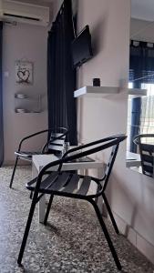 2 sillas negras en una habitación con TV en Meerithic ROKKA ROOMS, en Vourvourou