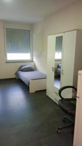 a bedroom with a bed and a chair and a mirror at Viva Zimmer in Heilbronn Zentrum in Heilbronn