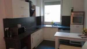 uma cozinha com armários brancos e um balcão preto em Viva Zimmer in Heilbronn Zentrum em Heilbronn