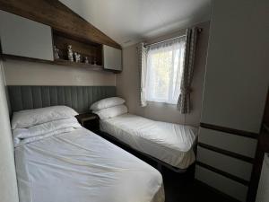 two beds in a small room with a window at Stunning Caravan With Decking At Azure Seas In Suffolk Ref 32055az in Lowestoft