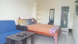 Habitación con cama, sofá y mesa. en Aranmagan Paradise, en Tiruchchendūr