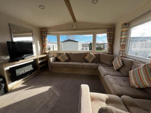 a living room with a couch and a flat screen tv at Lovely 6 Berth Caravan At Cherry Tree Holiday Park, Ref 70403c in Great Yarmouth