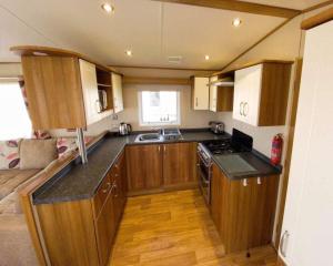 a small kitchen with wooden cabinets and a stove at SYCAMORES 15 in Reighton