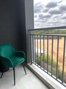 a green chair sitting on a balcony looking out at a field at White Oasis in Gaborone
