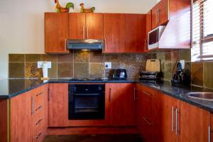 a kitchen with wooden cabinets and a stove top oven at Sondela Nature Reserve & Spa Makhato Lodges in Bela-Bela