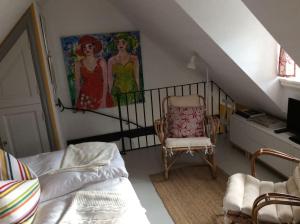 uma sala de estar com uma cadeira e um quadro na parede em Huset i gränden - granne med havet em Trelleborg