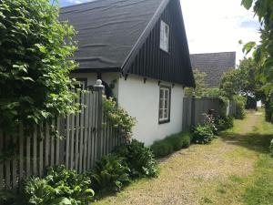 uma casa branca com um telhado preto e uma cerca em Huset i gränden - granne med havet em Trelleborg