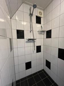 een badkamer met een douche met zwarte en witte tegels bij Zomerhuis Beach EnJoy in Egmond aan Zee