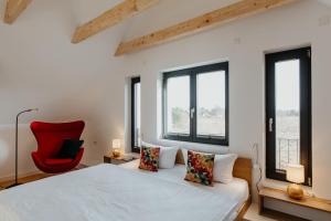 a bedroom with a bed and a red chair at SandDorn 1 und 2 in Pruchten